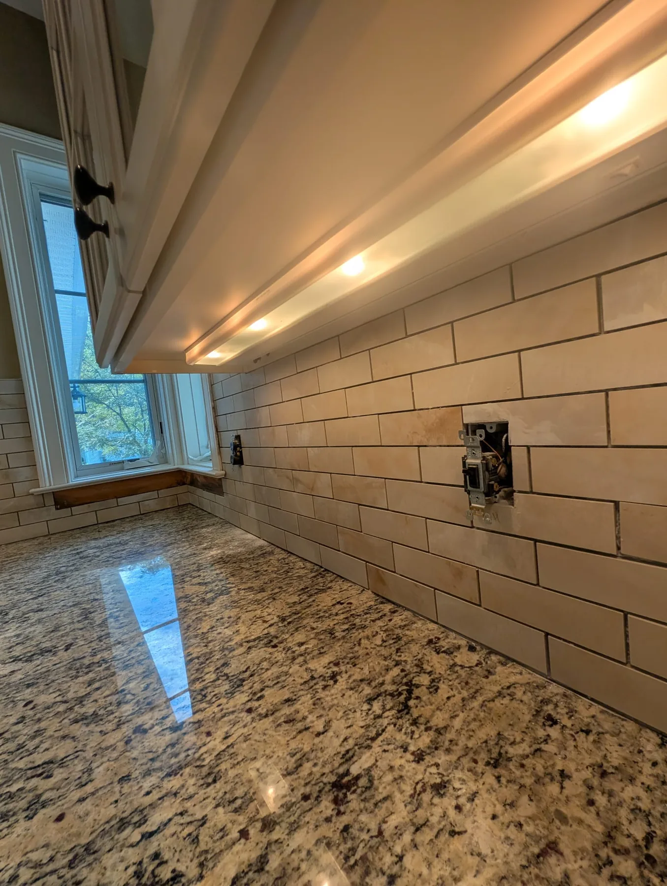 Kitchen range wall with white subway tile and speckled counter in Simsbury