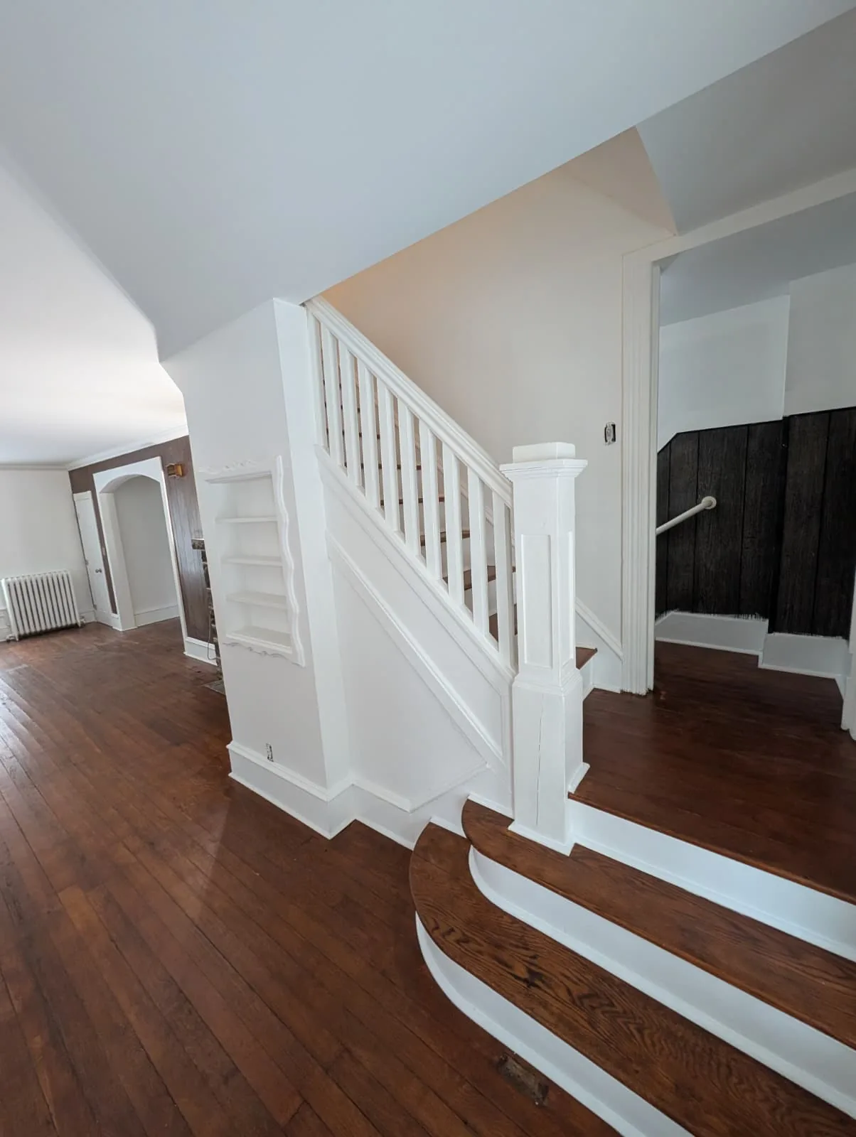 Curved hardwood stair landing and white railing in Glastonbury, Connecticut